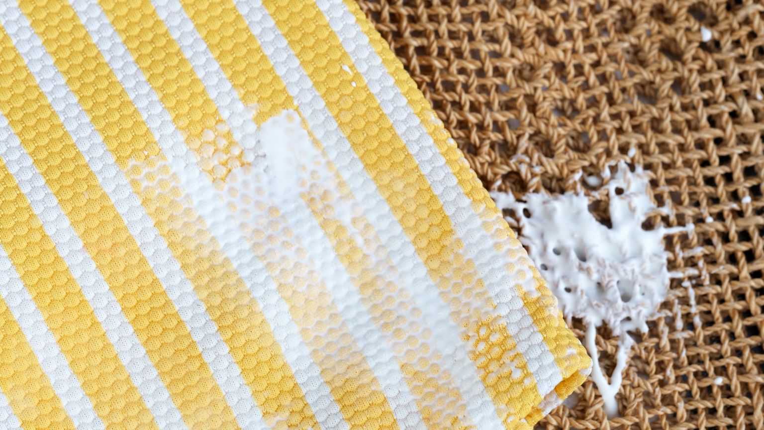 Come togliere macchie di crema solare dai tessuti: immagine di un alone di protezione solare su un asciugamano.