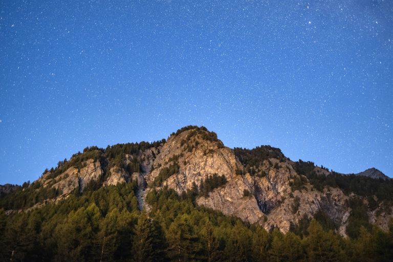 Il Parco Nazionale del Gran Paradiso di notte, con un cielo stellato che illumina il paesaggio montuoso, perfetto per usare un gadget da campeggio che illumina la notte.