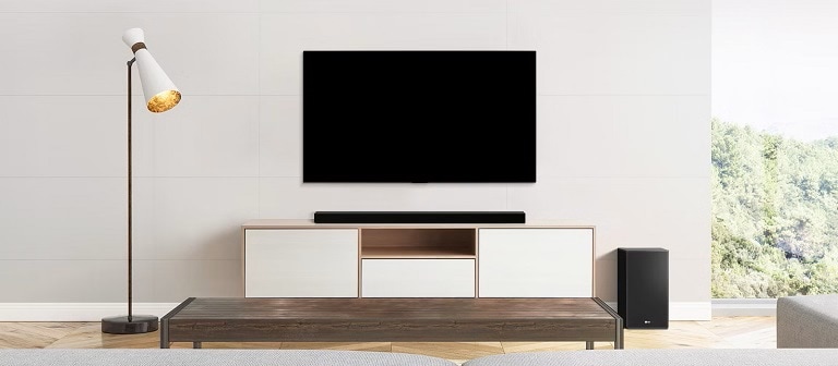 Soggiorno moderno con TV a schermo piatto, soundbar su mobile minimalista, lampada a sinistra e subwoofer a destra.