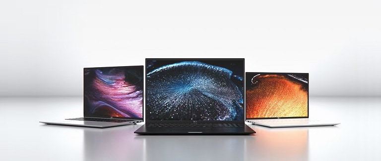 Tre laptop di diverse dimensioni, posizionati frontalmente, che mostrano immagini astratte sugli schermi.