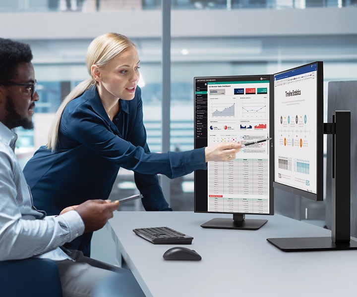 Due impiegati, un uomo e una donna, discutono guardando il monitor in ufficio.