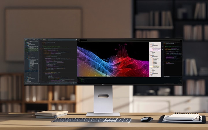 Un moderno setup da ufficio domestico con un ampio monitor ultra-wide LG che mostra dashboard e grafici di dati, accompagnato da una tastiera e un mouse wireless su una scrivania in legno.