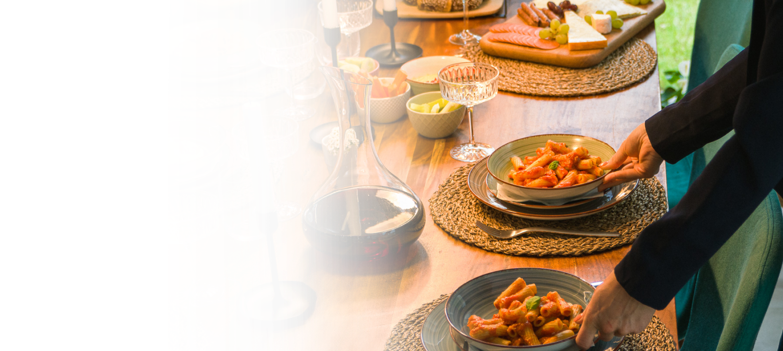 Una donna che prepara una festa a casa dispone la pasta su un tavolo da pranzo pieno di cibo.