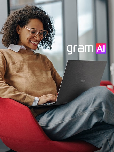 Una persona seduta comodamente su una sedia moderna, che lavora su un portatile LG Gram e sorride. Il logo “gram AI” è ben visibile nell’immagine.