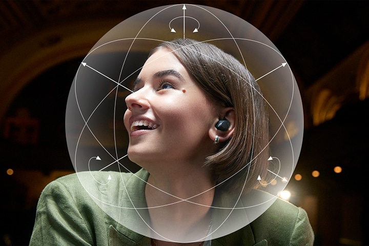 Una donna che indossa gli auricolari T90S sorride. Intorno alla sua testa viene mostrata una sfera illustrativa per enfatizzare la funzione Dolby Head tracking™.