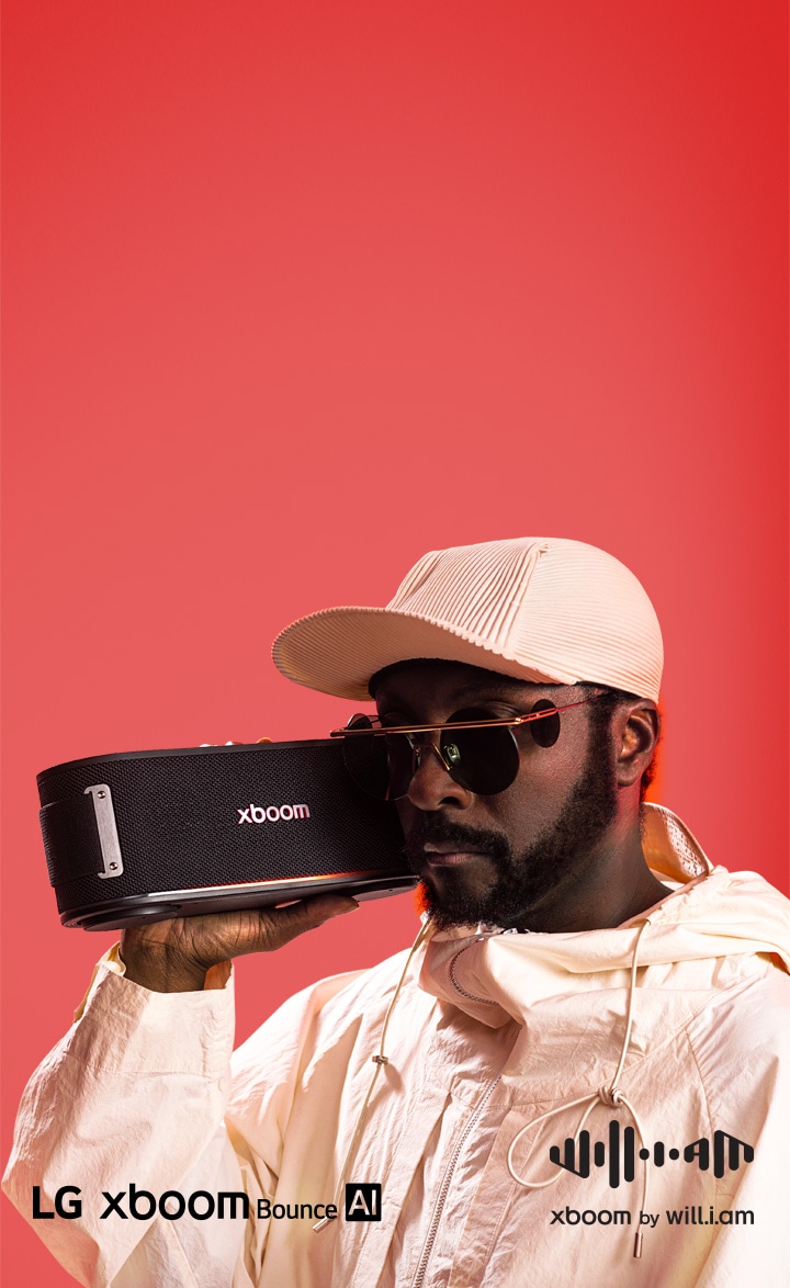 Will.i.am, vestito di bianco e con occhiali da sole, tiene xboom Bounce proprio accanto al viso.