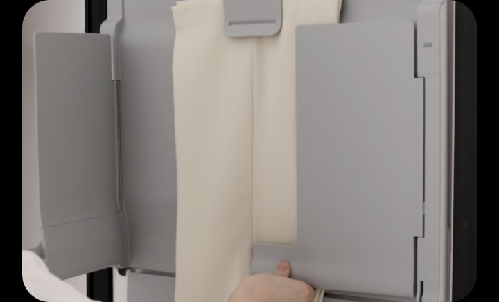 LG StylerでマルチプレートのEZ Fit PantsPress™を使用して、パンツのシワを取り除き折り目を復元している人。