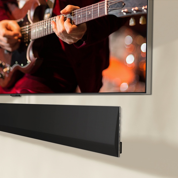 Угловой вид снизу на саундбар LG Soundbar, и телевизор LG TV крепится на стене.