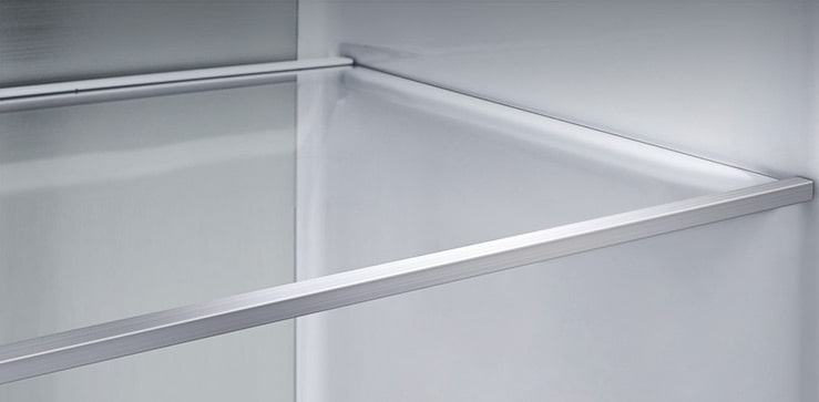 Вид по диагонали на полку с панелями цвета «металлик» на внутренней стороне холодильника.
