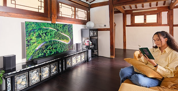 El huésped se relaja mientras lee un libro frente al televisor LG.