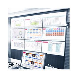 En una pantalla rectangular más grande se proyectan una serie de pantallas que muestran gráficos y diagramas, mientras que en la parte del frente se coloca el monitor de una computadora. 