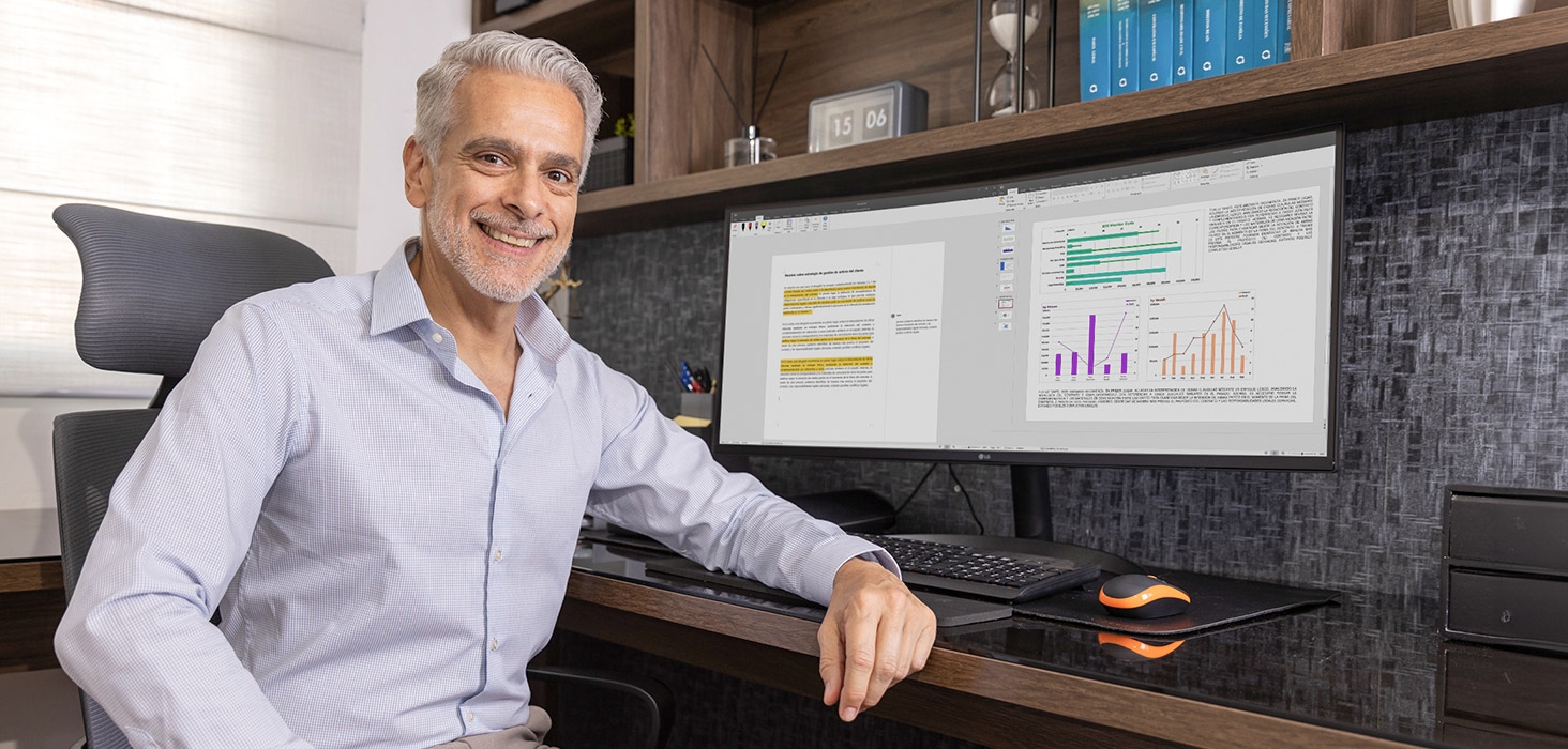 Luis sonriendo en su silla, con su monitor LG UltraWide configurado para el trabajo.