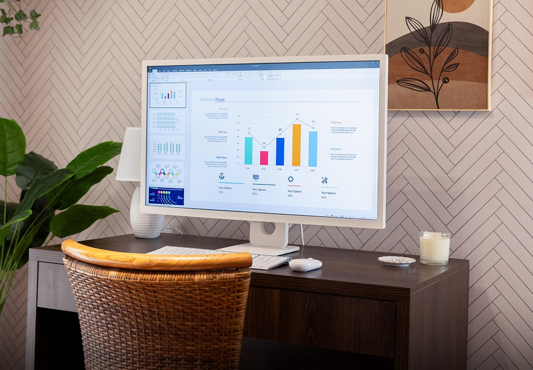 Monitor LG MyView Smart en el escritorio. Silla marrón, planta y pintura en la pared.