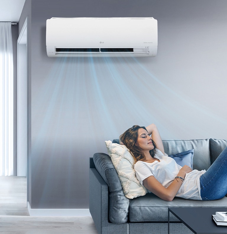 Una mujer descansa en un sofá con el aire acondicionado LG encendido, enfriando la sala con corrientes de aire azules.