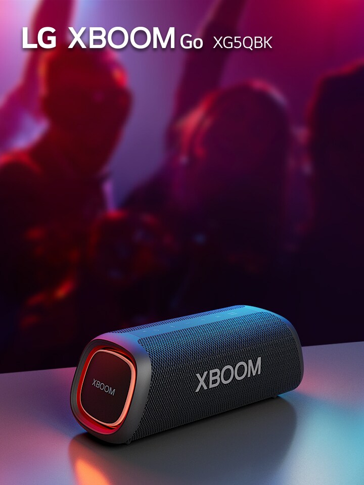 LG XBOOM Go XG5 está colocado sobre la mesa de metal con una luz naranja encendida. Detrás de la mesa, la gente disfruta de la música.