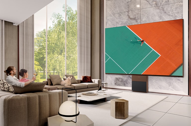 Una pareja está viendo un partido de tenis en el gran LG MAGNIT de ultra alta definición en la sala de estar.