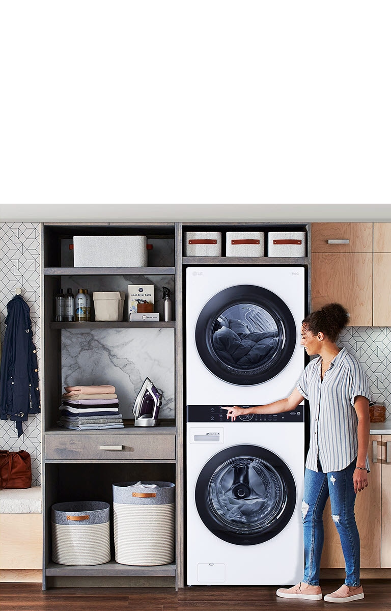 La LG WashTower™ con diseño estilizado maximiza el espacio en una sala de lavado organizada con muebles de almacenamiento.