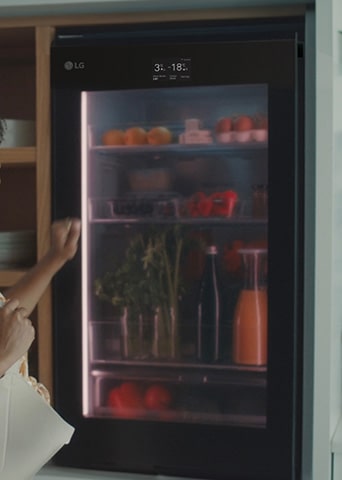 Imagen de una mujer tocando la parte superior de un refrigerador.	