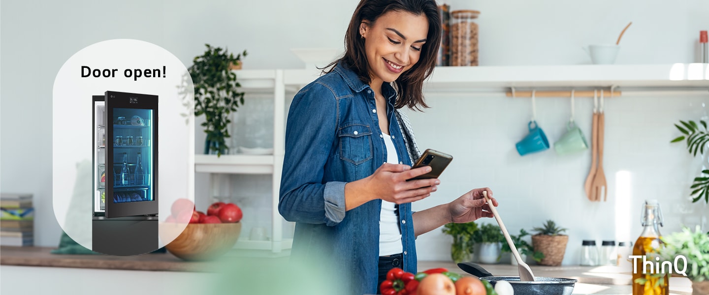 Imagen de una mujer cocinando mientras mira su teléfono y un refrigerador con la puerta abierta.	