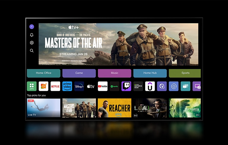 Un primer plano de la pantalla de un televisor LG que muestra los botones Home Office, Game y Music sobre un cartel de Masters of the Air se aleja para mostrar el televisor montado en una pared de una sala de estar. Los siguientes logotipos se muestran en la pantalla del televisor en la imagen: LG Channels, Netflix, Prime Video, Disney TV, Apple TV, YouTube, Spotify, Twitch, GeForce Now y Udemy.