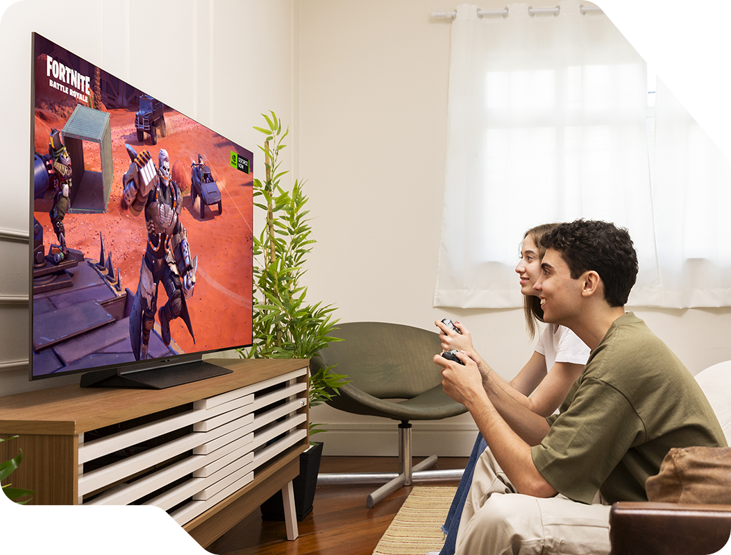 Bruno y su novia están jugando FORTNITE en un televisor LG C4 OLED en la sala de estar. Lado izquierdo de la sala. Planta y cortina en la parte trasera.