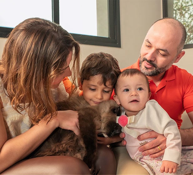 Un corte familiar, cinco de ellos sentados de cerca, incluyendo un gato oscuro y marrón que se abraza en los brazos de la madre.