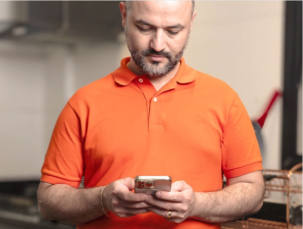 Padre llevaba camisas naranja con barba, manejando su teléfono móvil.
