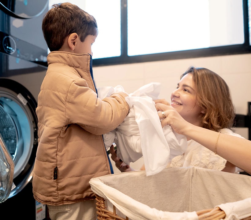 Mamá agradece a su hijo por ayudar con la lavandería. Ella tiene una gran sonrisa en su rostro, mirando a su hijo con alegría y amor.