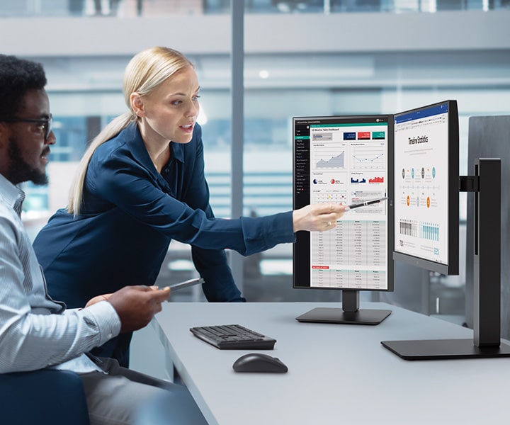 Dos empleados discutiendo en la oficina mientras ven el monitor.