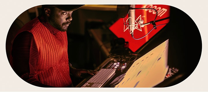 will.i.am está trabajando en el estudio mirando una pantalla colocada debajo de un micrófono.