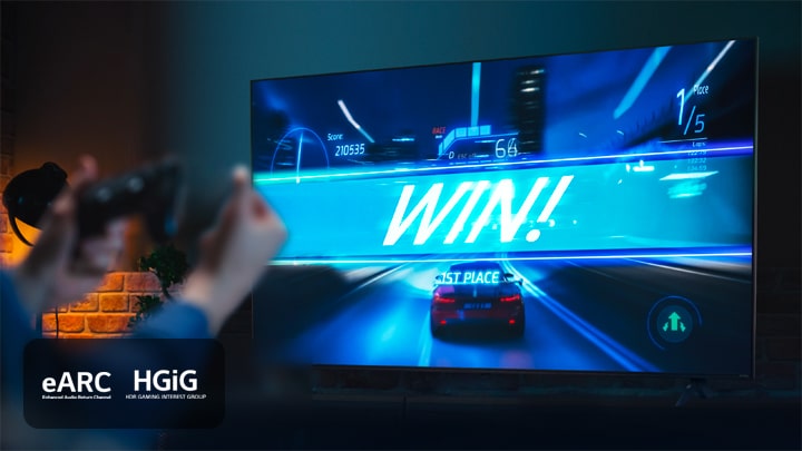 Een autoracegame aan de finish met een bordje met ‘WIN!’, terwijl de speler een joystick in de hand heeft. eARC-, HGiG-logo staan in de hoek links onderin.