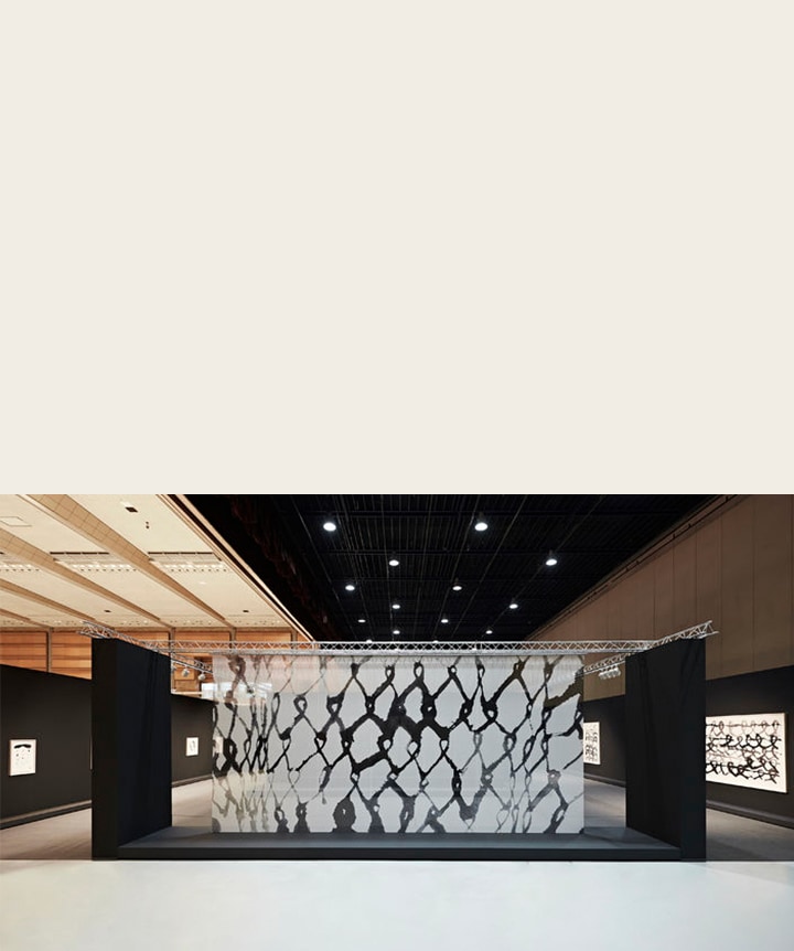 Kunst op een doorzichtig paneel in een tentoonstellingsruimte.