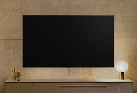 Een aan de muur gemonteerde LG TV lijkt uitgeschakeld, maar de Always Ready-functie wordt ingeschakeld. Het toont informatie en wisselt daarna door verschillende kunstwerken.