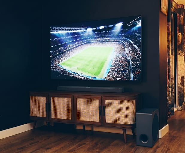 Close-up van een soundbar onder een tv op een houten meubel.