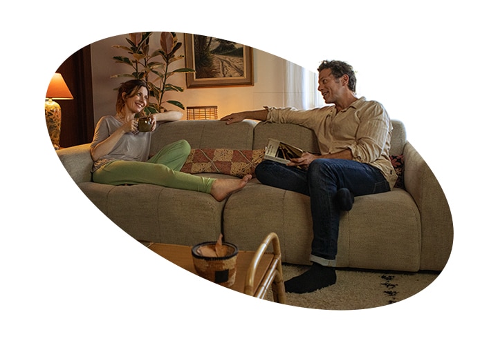 Een volwassen vrouw en een man zitten op een bank in huis en praten met een glimlach. Er staat een Stilte Markering-certificeringslogo naast de afbeelding.