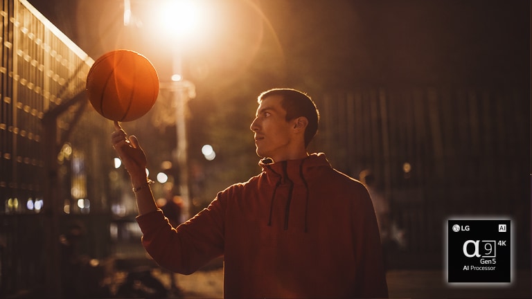 man op basketbalveld in de nacht draait een basketbal op zijn vinger