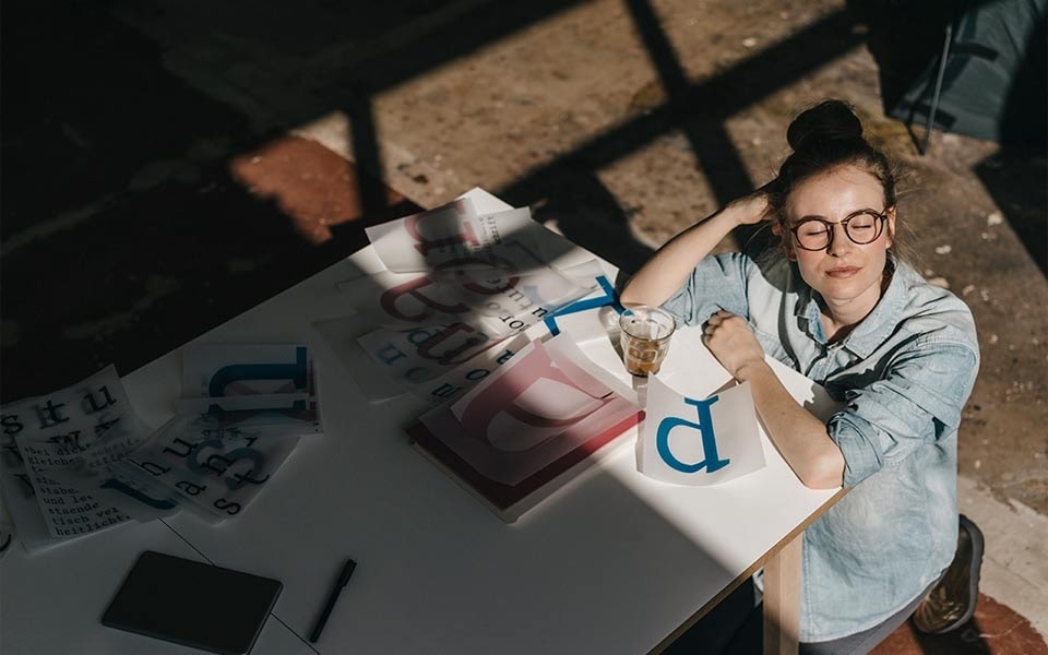 Een vrouw kijkt weg van haar scherm om haar ogen te laten rusten