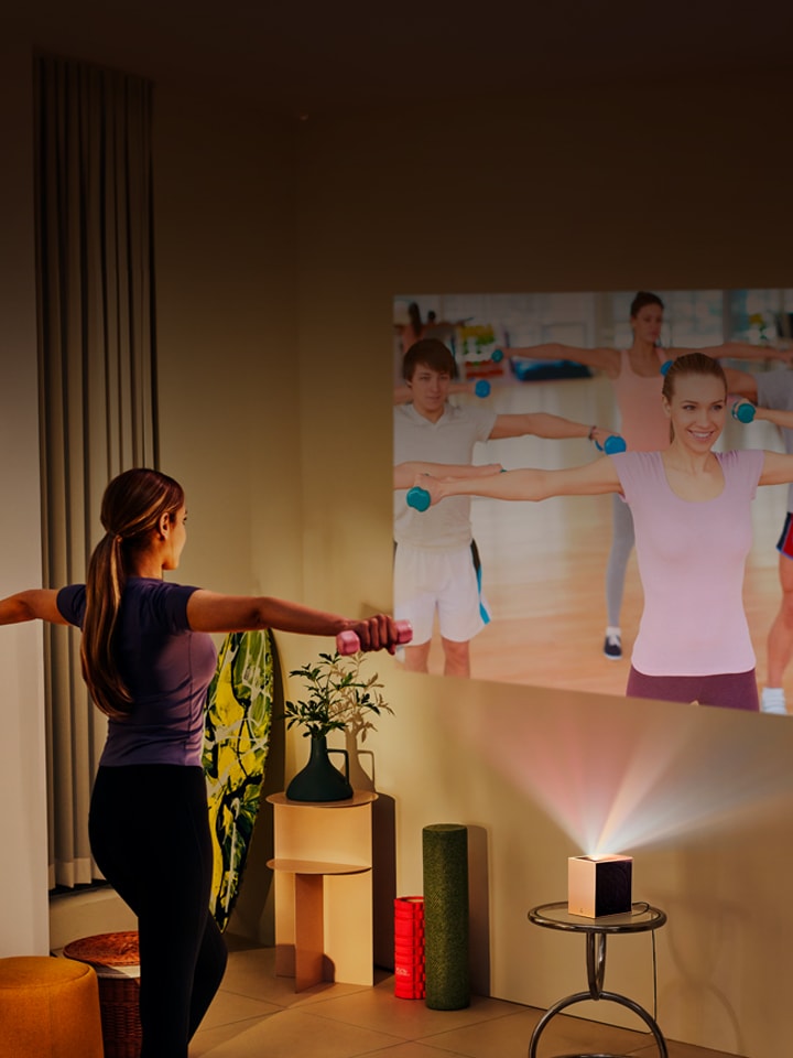 Vrouw doet yoga met LG CineBeam-projectie op de achtergrond.