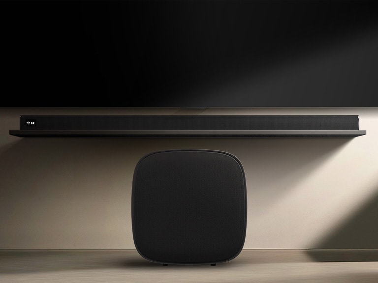 LG Sound Suite W7 woofer geplaatst onder een tv met een soundbar, wat een eenvoudige draadloze geluidsuitbreiding voor een meeslepend thuisstereosysteem laat zien