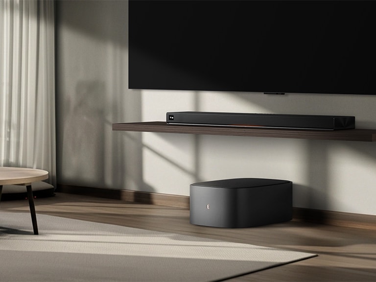 LG Sound Suite W7 woofer geplaatst onder een tv met een soundbar, wat een eenvoudige draadloze geluidsuitbreiding voor een meeslepend thuisstereosysteem laat zien