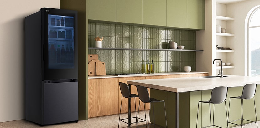 The side view of lg bottom freezer refrigerator with instaview in a kitchen with green cabinets and a stylish island.