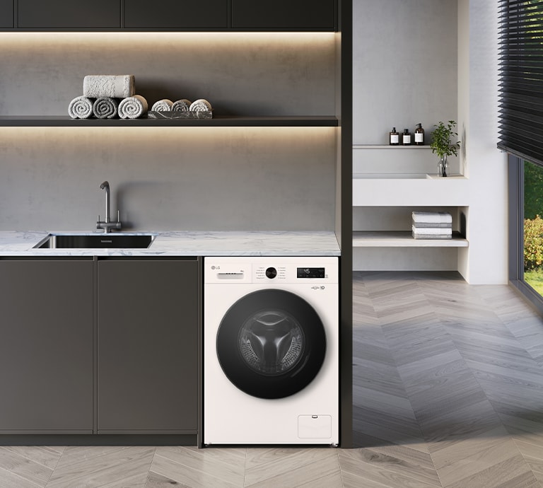 Image shows stylish exterior of a white washing machine with a black glass door in a laundry setting.