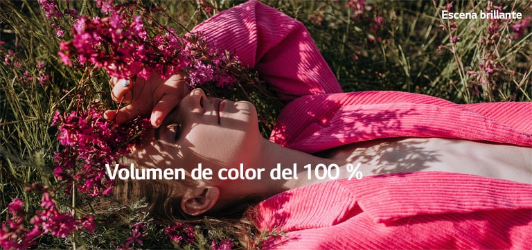 El video muestra a una jovencita con la mano sobre los ojos, mientras yace en un campo de césped y flores rosas. A medida que se reproduce el video, los colores se tornan más intensos y el indicador de porcentaje del volumen de color aumenta del 70 % al 100 %.