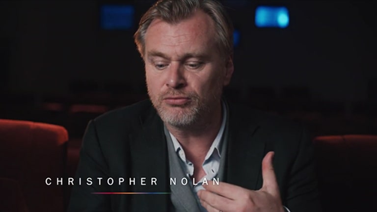 El director Christopher Nolan haciendo una entrevista en una sala de cine