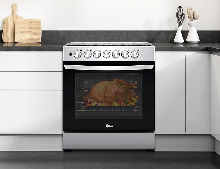 Horno LG en cocina moderna con pavo asándose acompañado de vegetales.