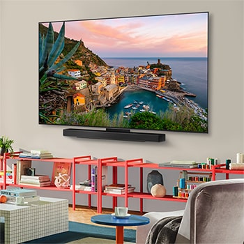 Vista amplia de una sala de estar elegante y colorida. Smart TV LG OLED evo AI C5E 4K montada en la pared con una LG Soundbar debajo. El diseño de la televisión se integra bien en el espacio. En la pantalla de la televisión se ve una colorida obra de arte. 