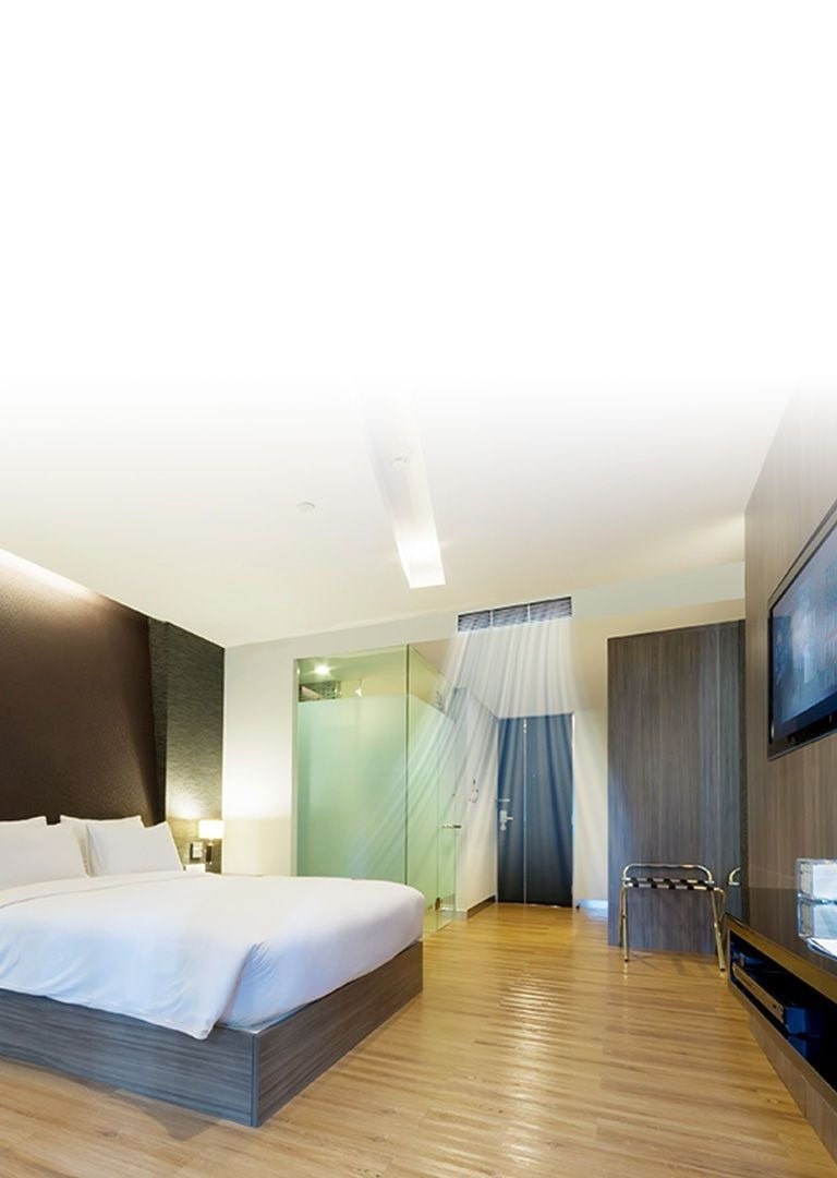 A ceiling concealed duct supplying blue-colored air current in a hotel room with brown toned walls and a queen bed covered with white beddings.