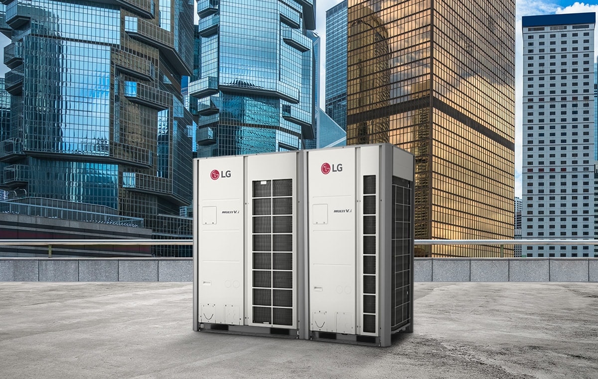 Two LG MULTI V i units stand side by side on a rooftop, front-facing view, against a backdrop of towering skyscrapers cloaked in the glass.