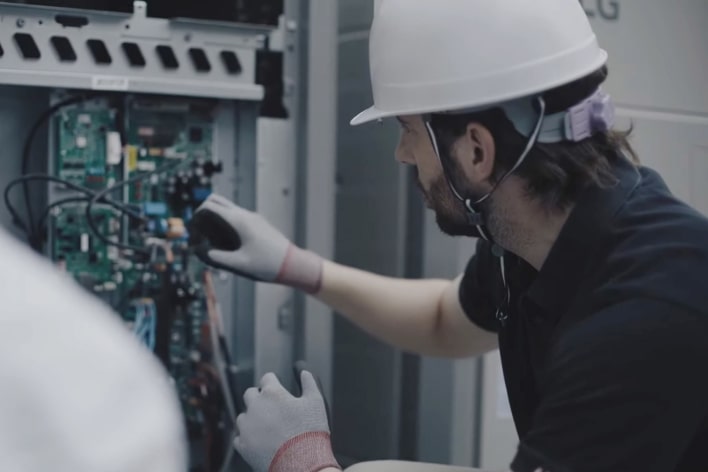 An installer wearing a safety helmet is checking the condition with the inside of the product open.	