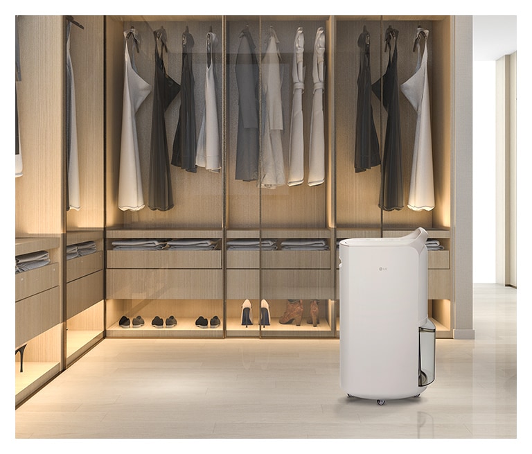 It shows calming beige color LG Puricare™  Dehumidifier is placed in a dressing room full of clothes.